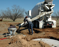 Concrete mixer truck and crew installing a new septic tank near Brownwood, TX