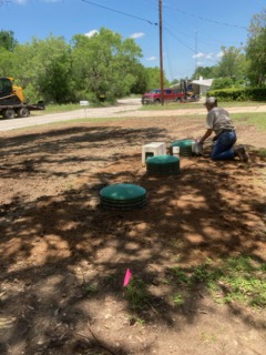 Technician finishing septic riser lid installation at a residential property in Central Texas
